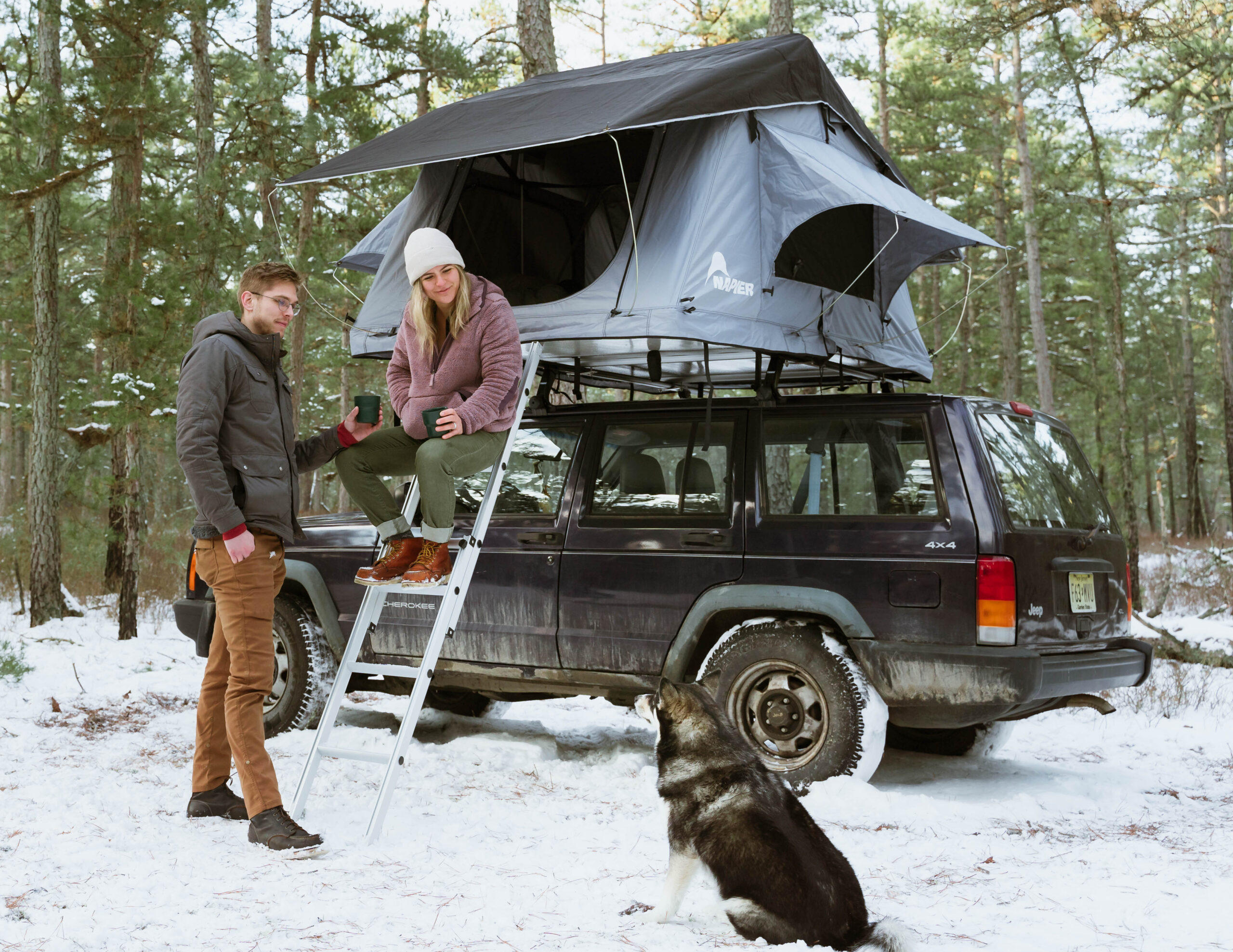 couple camping in a rooftop tent in the snow