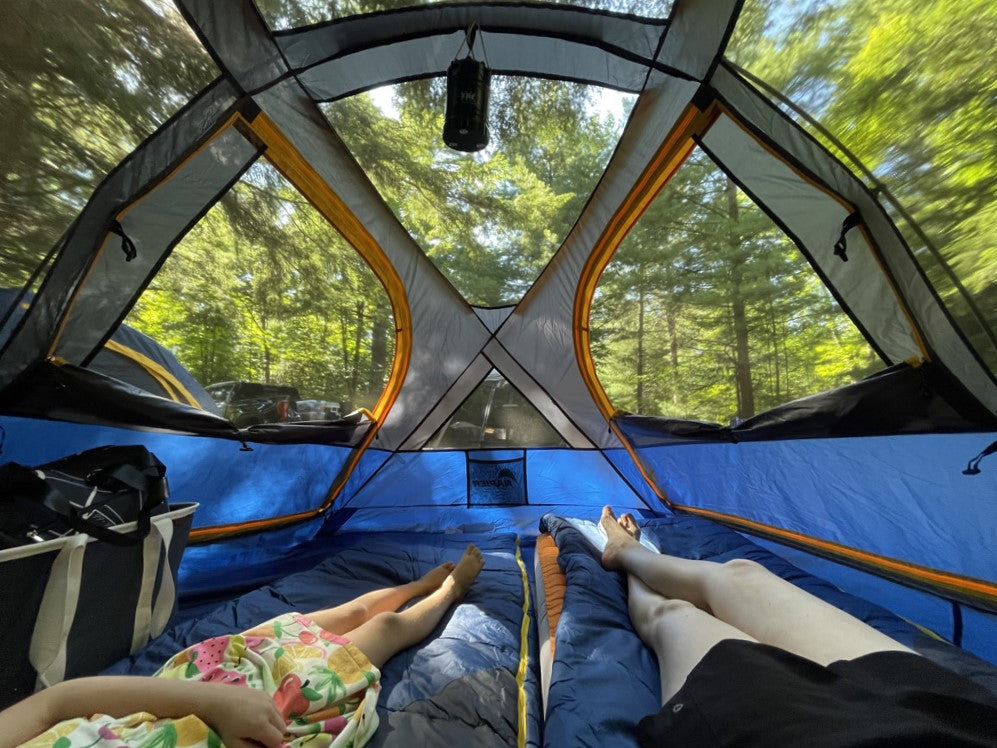 two people laying down inside a tent with screen roof