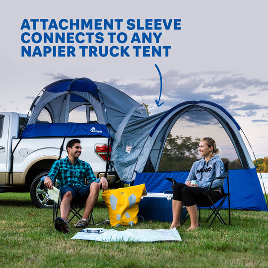 Couple sitting on chairs outside of their truck tent and link ground tent attachment camping set up