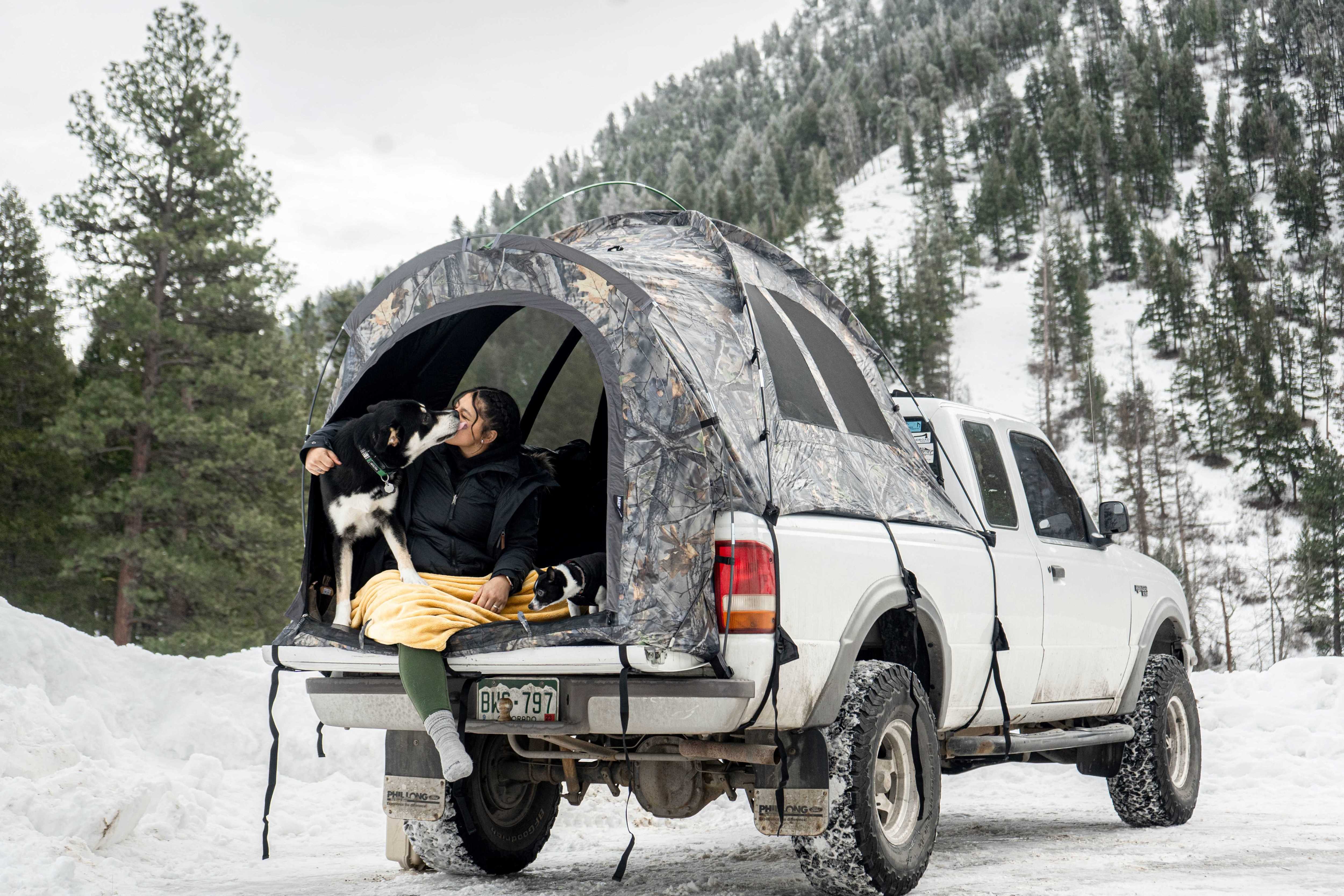 Girl and dog inside camp truck tent set up in the snowy mountains