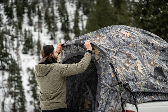 Man setting up a camo Napier camo truck tent