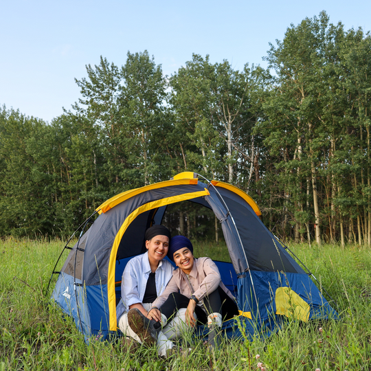 two people sitting inside a napier ground tent in a field