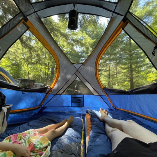 two people laying down inside of a tent with screen ceilings