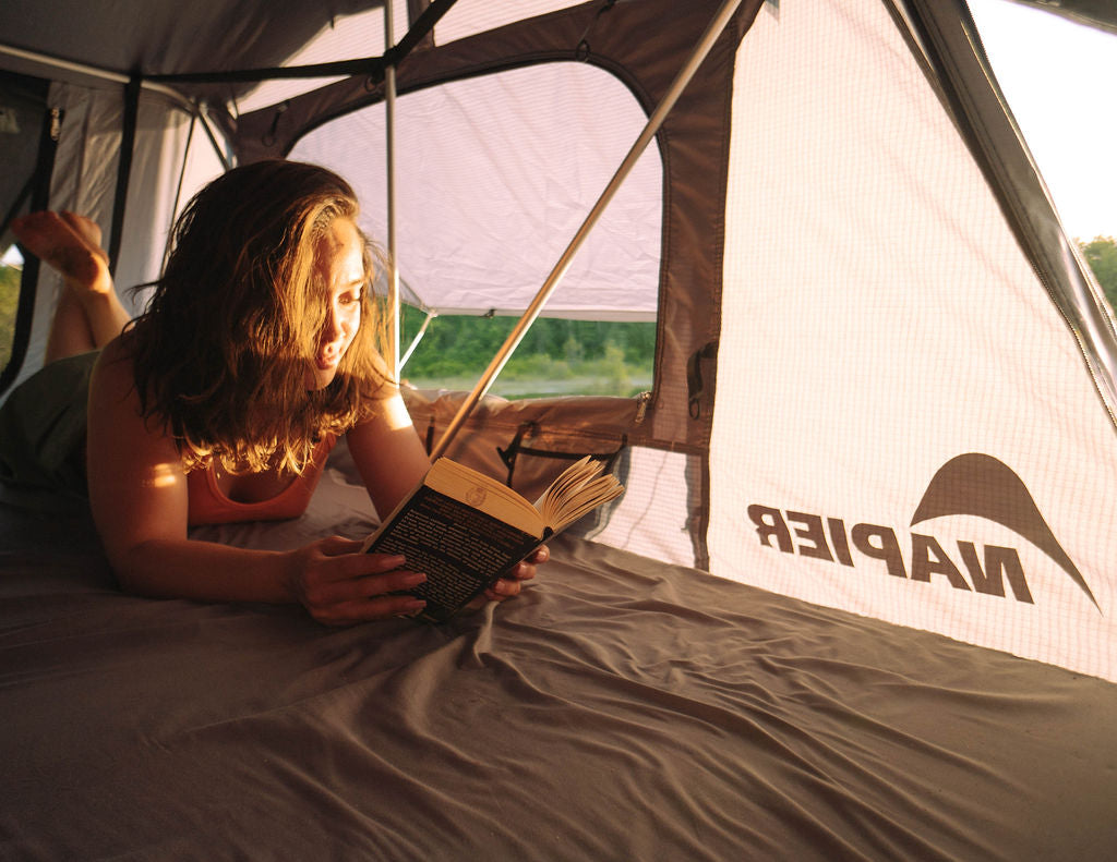 girl reading a book inside a napier rooftop tent