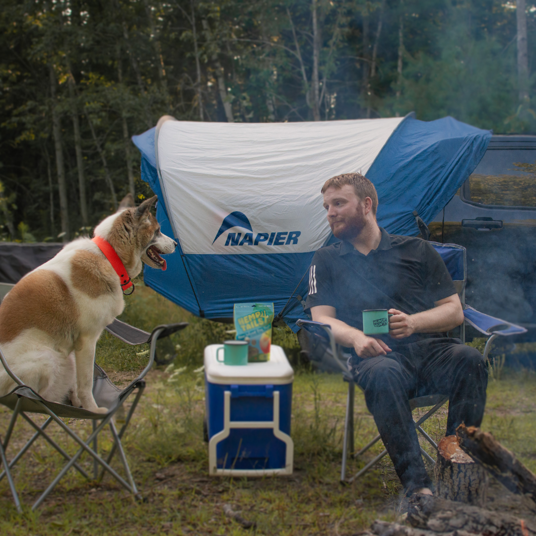 Man and Dog sitting with Napier Maverick Truck Tent