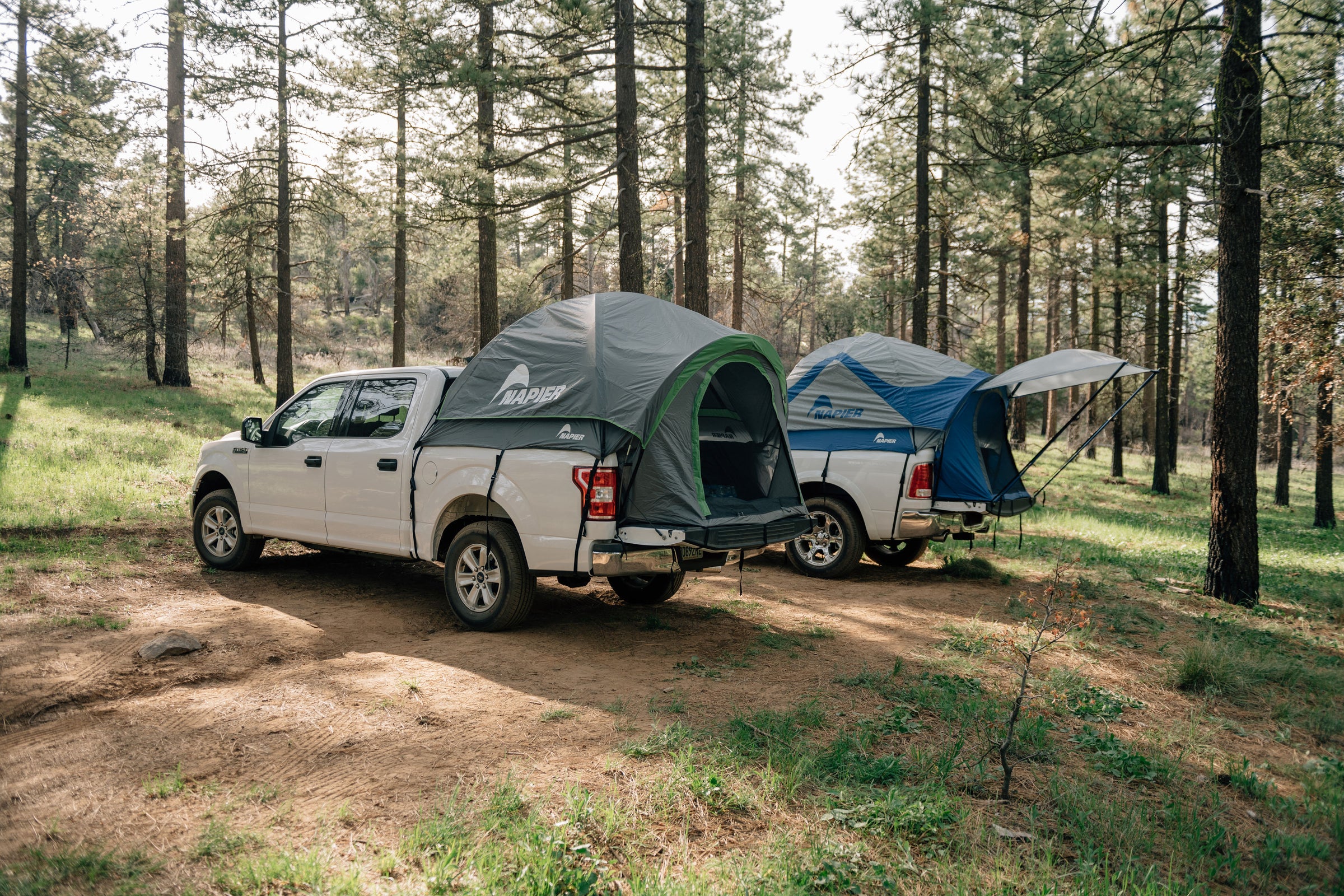 Two napier truck bed tent camping and overlanding set ups on trucks in the forest