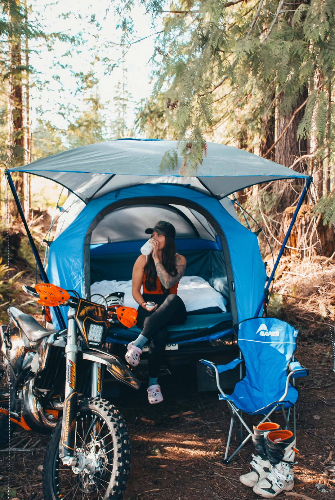 girl sitting inside a napier truck tent camping set up with bike and chair