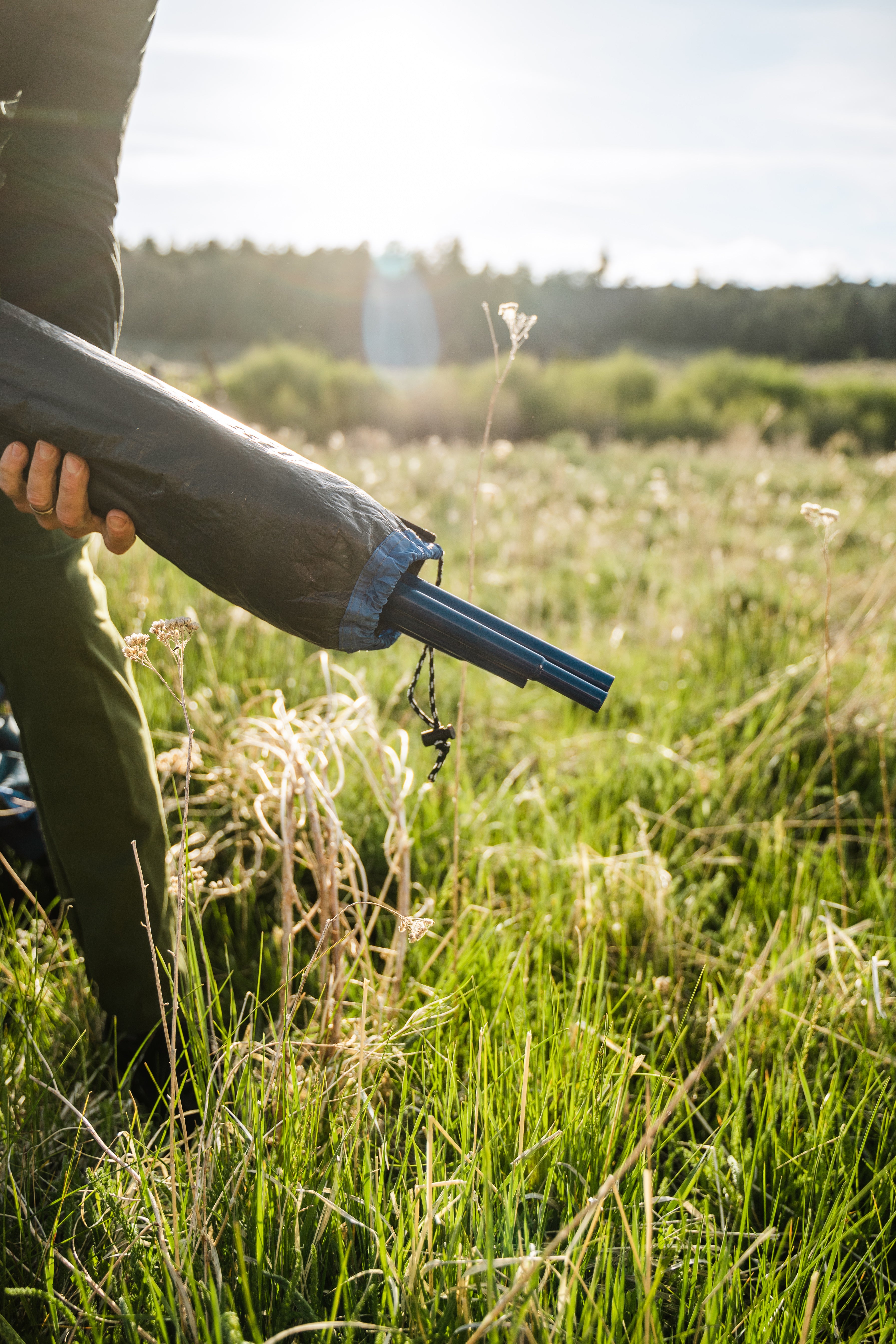 Person holding tent replacement poles in a field